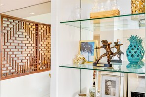 A modern interior with a decorative wooden wall, a glass display shelf with various items, and a framed picture. - Beachfront Property W/sand Access at Waikiki Shore Condo With Full Kitchen (Honolulu)