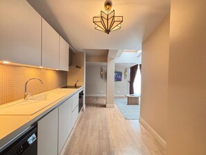A modern kitchen with a built-in dishwasher, a countertop sink, and a unique geometric light fixture. - Top-floor terrace apartment near Galataport (Istanbul)