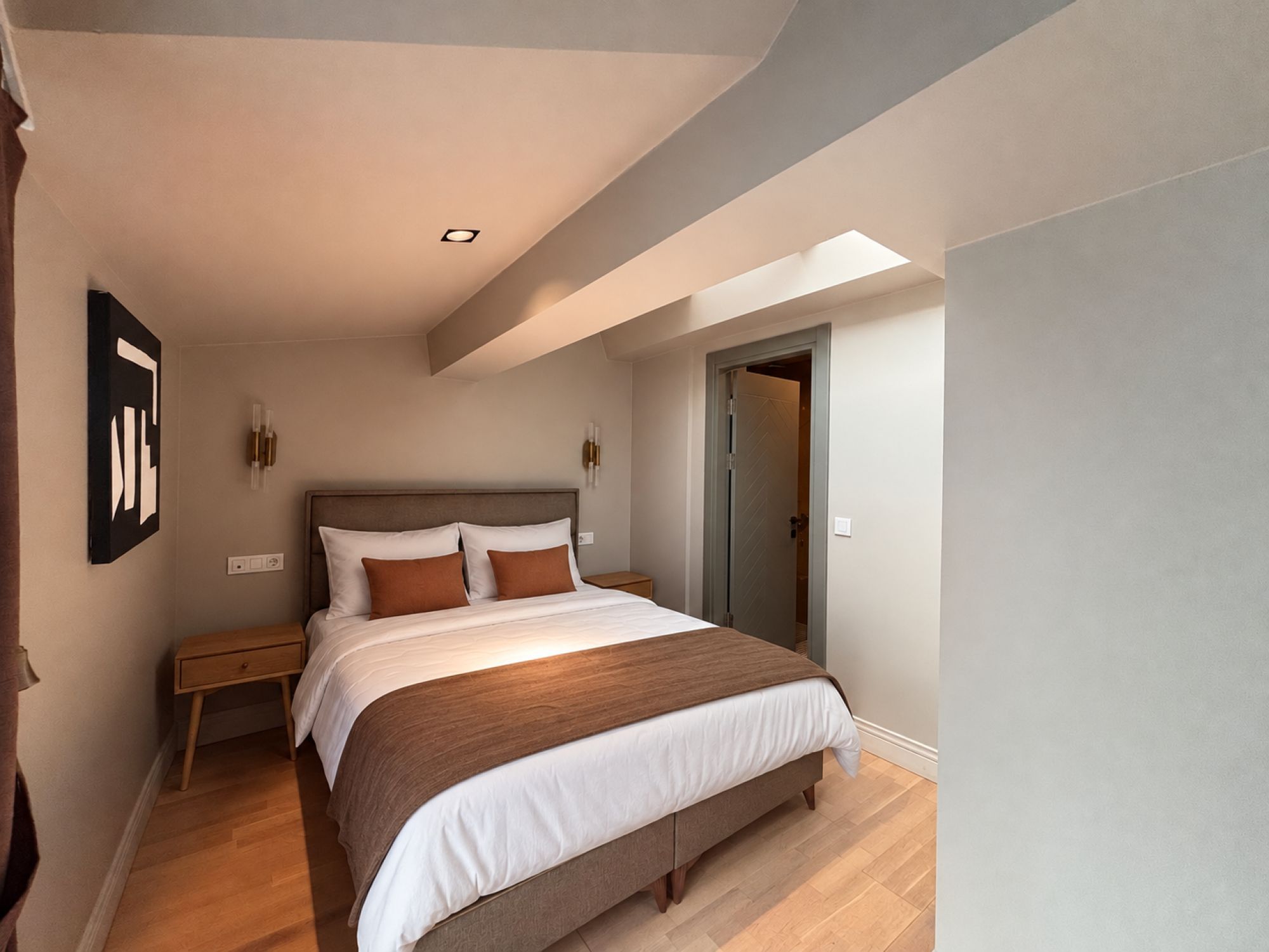 Un dormitorio moderno con una cama grande, una mesita de noche y una puerta que da a otra habitación.