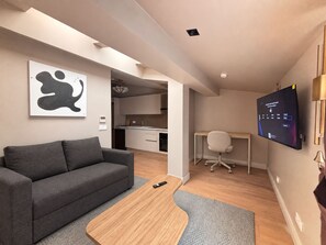 A modern living room with a grey sofa, a wooden coffee table, and a flat-screen TV mounted on the wall. - Top-floor terrace apartment near Galataport (Istanbul)