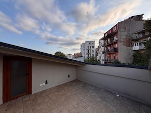 A rooftop terrace with a door, a tiled floor, and a view of surrounding buildings. - Top-floor terrace apartment near Galataport (Istanbul)