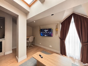 A modern hotel room with a flat-screen TV mounted on the wall, a wooden desk, a chair, and a large window with curtains. - Top-floor terrace apartment near Galataport (Istanbul)