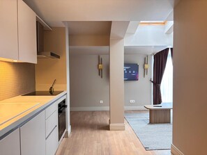 A modern kitchen with a built-in oven, a dining area with a bench, and a flat-screen TV mounted on the wall. - Top-floor terrace apartment near Galataport (Istanbul)