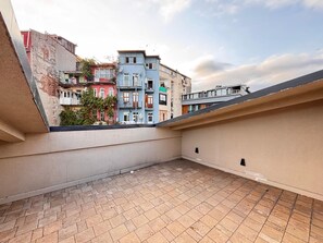 A rooftop terrace with a tiled floor, surrounded by multi-story buildings with balconies. - Top-floor terrace apartment near Galataport (Istanbul)