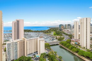 A high-rise building with multiple floors, a marina with boats, and a clear view of the ocean. - Ocean-sunset Views Designer Condo at The Watermark W/great Building Amenities (Honolulu)