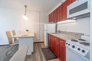 A compact kitchen with a dining area, a built-in stove, and a refrigerator. - Ocean-city Views at Marine Surf Close to the Beach W/parking & Full Kitchen (Honolulu)