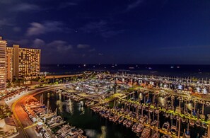A marina with numerous boats docked, surrounded by buildings and a curved road. - Ocean-marina and Fireworks Views at Ilikai Marina Short Stroll to the Beach (Honolulu)