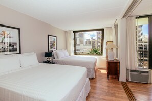 A hotel room with two beds, a nightstand, a lamp, a window with curtains, and a radiator. - Ocean-city Views Family Getaway at Waikiki Banyan Half a Block to the Beach (Honolulu)