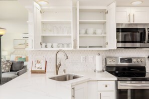 A modern kitchen with white cabinetry, a stainless steel sink, and a built-in oven. - Ocean-marina Sunset Views Condo With Full Kitchen at Ilikai Hotel by Beach (Honolulu)