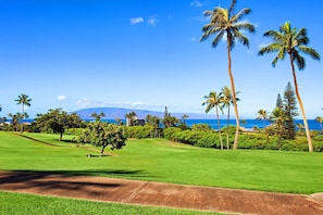 A golf course with a clear view of the ocean and a mountain in the distance. - Maui Kaʻanapali Condo - Ocean View, Walk to Beach (Lahaina)
