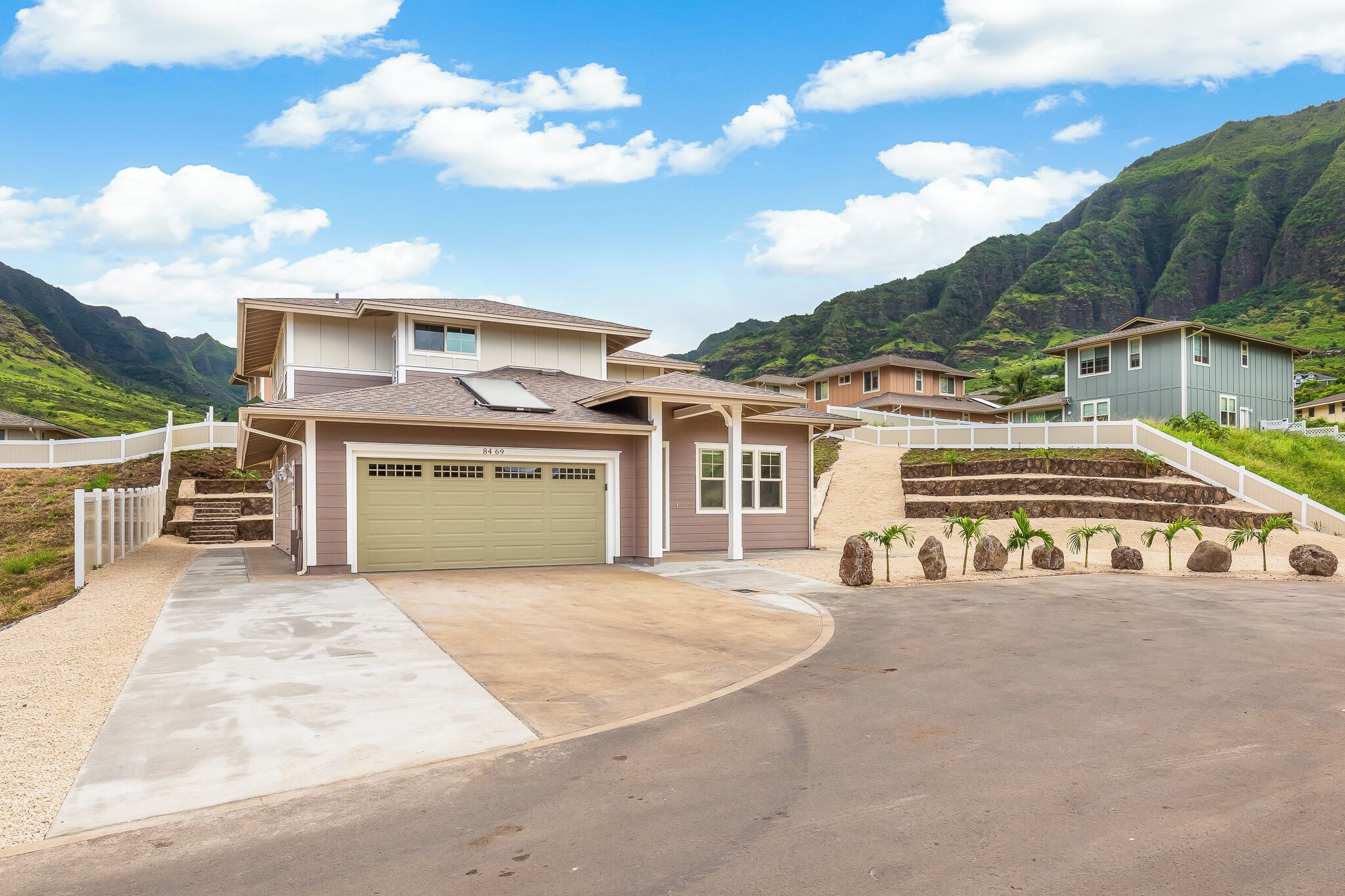 A two-story house with a garage, a driveway, and a stone staircase leading to the entrance.
