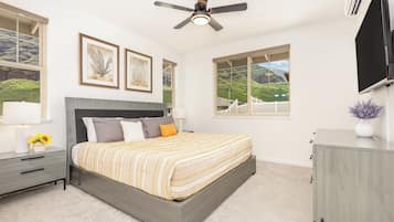A bedroom with a bed, bedside tables, a ceiling fan, and large windows with a view.