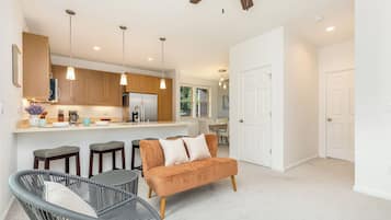 A modern kitchen with wooden cabinets, a stainless steel refrigerator, and pendant lights.