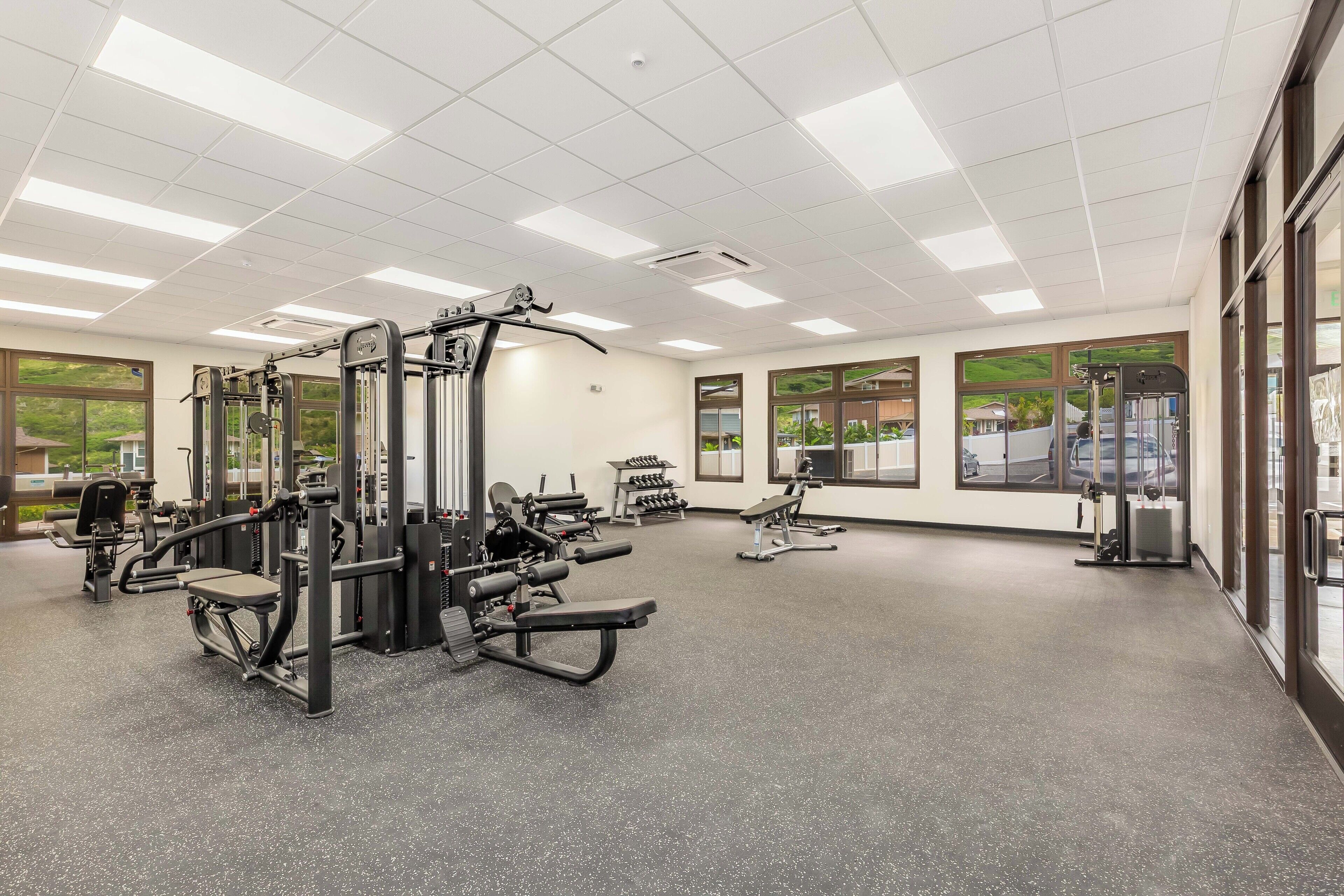 Une salle de sport équipée de divers appareils d’exercice, dotée de grandes fenêtres et d’un intérieur propre et bien éclairé.