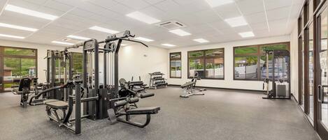 Une salle de sport équipée de divers appareils d’exercice, dotée de grandes fenêtres et d’un intérieur propre et bien éclairé.