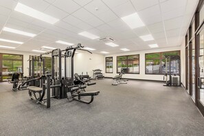 Ett gym med olika träningsmaskiner, stora fönster och en ren och väl upplyst interiör.