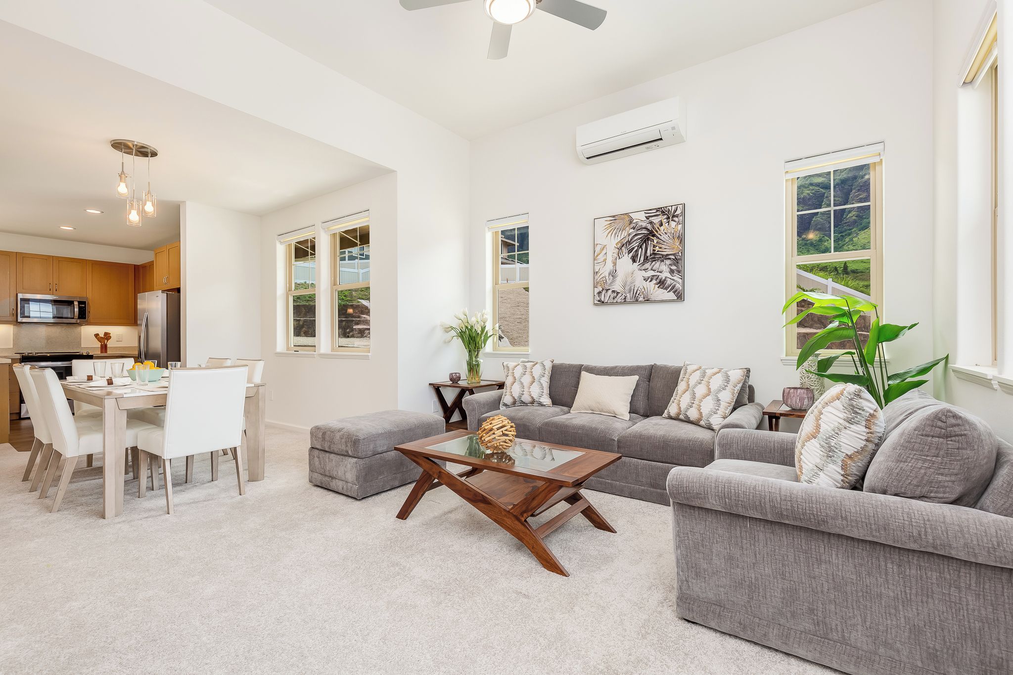 A modern living room with a grey sofa, a coffee table, and a dining area with chairs and a table.