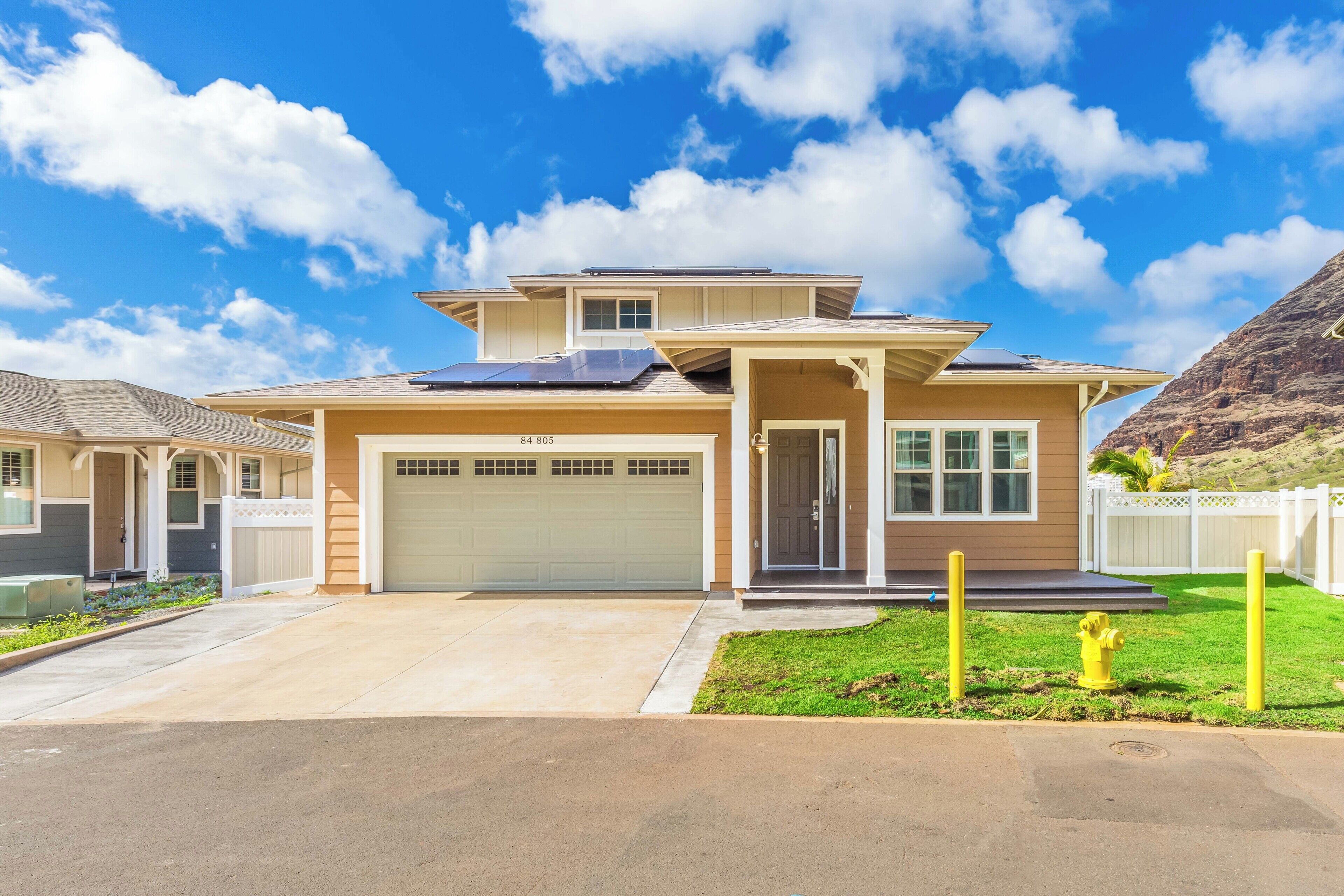 A modern two-story house with a garage, solar panels, and a well-maintained lawn.