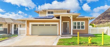 A modern two-story house with a garage, solar panels, and a well-maintained lawn.