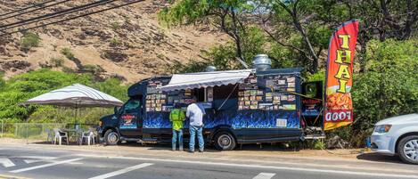 A food truck with a Thai food banner parked on a street.