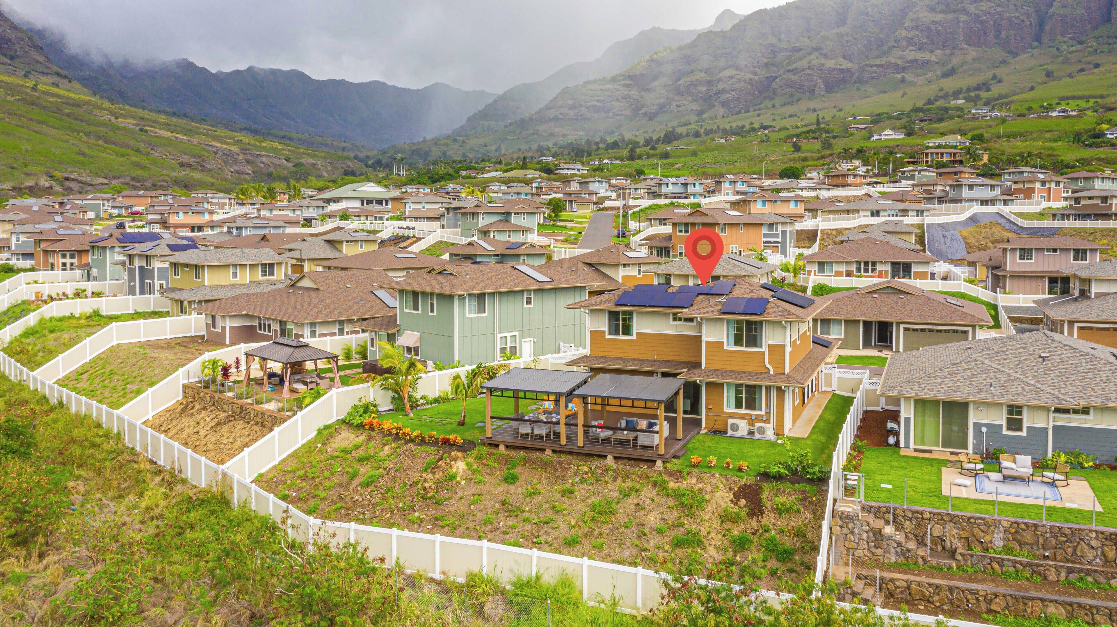 Zona residencial con casas, un marcador rojo indicando una ubicación y montañas al fondo.