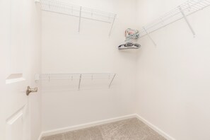A corner of a room with a white door, a beige carpet, and two metal drying racks mounted on the wall. - Ocean View Home for Family Fun Getaway Near Beach W/hot Tub and Bbq Grill (Waianae)