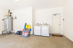 A laundry room with a water heater, washing machine, and dryer. - Ocean View Home for Family Fun Getaway Near Beach W/hot Tub and Bbq Grill (Waianae)