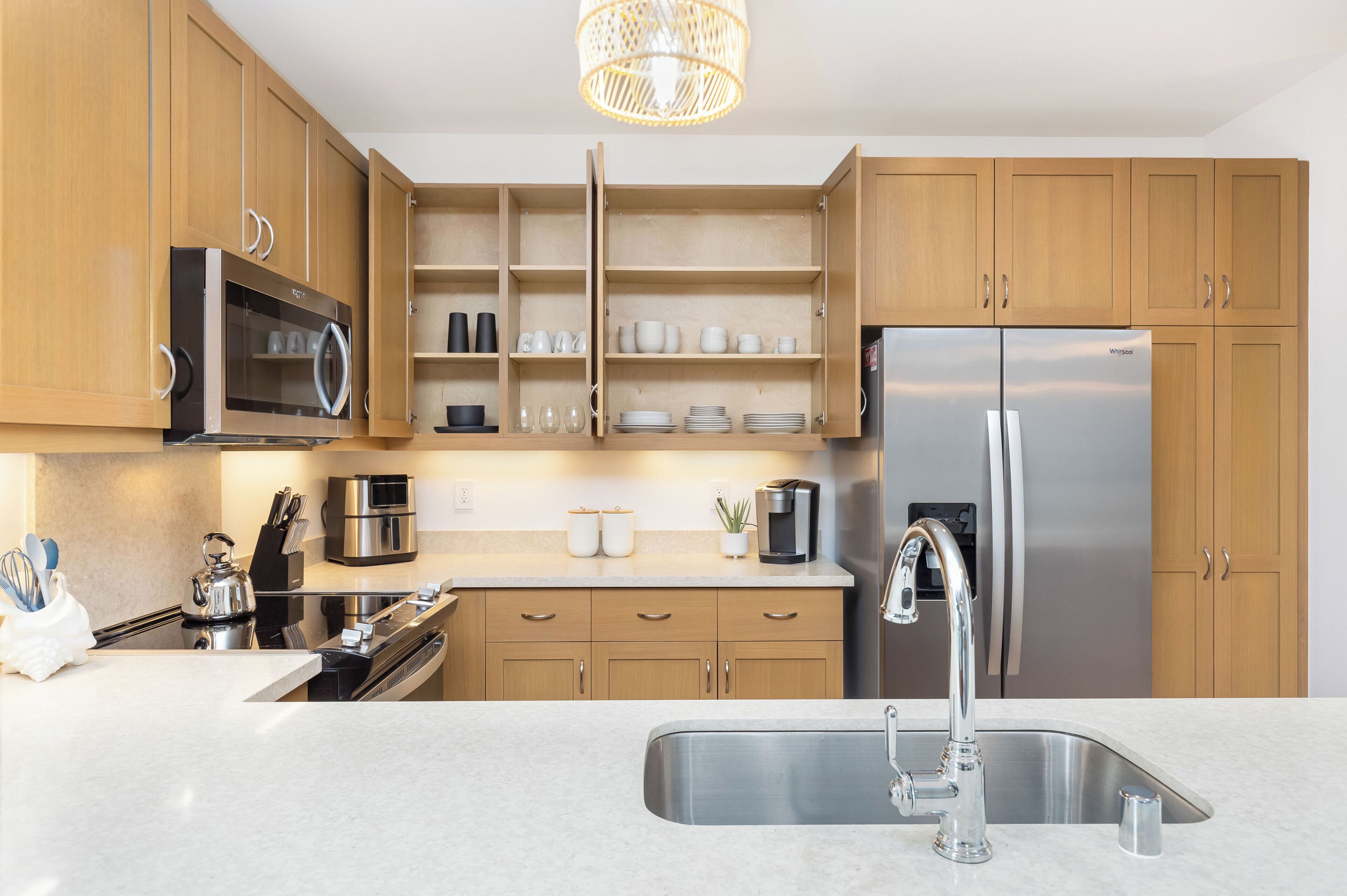 A modern kitchen with wooden cabinets, stainless steel appliances, and a built-in microwave.
