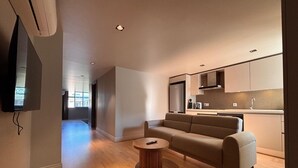Ein modernes Wohnzimmer mit einer Couch, einem Couchtisch und einem an der Wand montierten Fernseher.