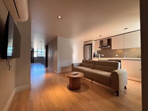 Una sala de estar moderna con un sofá, una mesa de centro y un televisor montado en la pared.