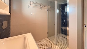 Ein modernes Badezimmer mit Duschkabine aus Glas, einer weißen Badewanne und einem Musterfliesenbelag.