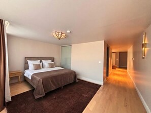Un dormitorio con cama, mesita de noche y piso cubierto de alfombra.