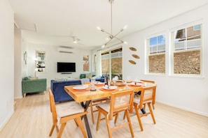 A modern living space with a dining area, a television, and a view of the outdoors. - Family Vacation Home W/ocean View at Makaha Valley in Secure Gated Community (Waianae)