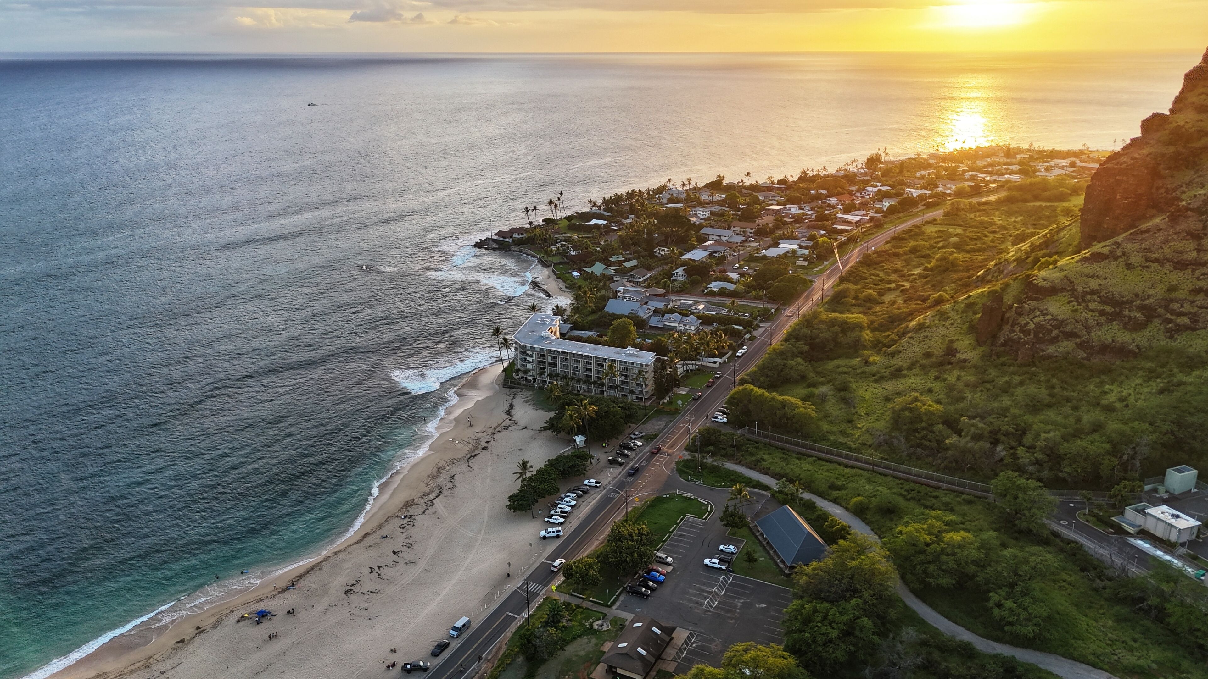 Vue aérienne d’une ville côtière avec une plage, une route et un immeuble à plusieurs étages.