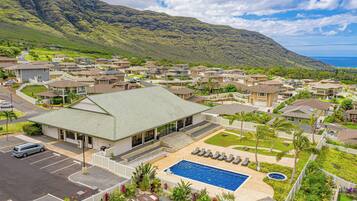 A residential area with houses, a swimming pool, and a view of a mountain and ocean.