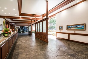 Eine Lobby mit Steinboden, Holzvertäfelung und gerahmten Kunstwerken an den Wänden.
