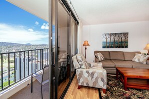 Ein Balkon mit Blick auf die Stadt, ein Sofa, ein Sessel, ein Couchtisch und ein Gemälde an der Wand.
