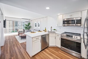 A modern kitchen with white cabinets, stainless steel appliances, and a wooden floor. - Ocean-lagoon Condo W/full Kitchen at Ilikai Hotel and Steps to the Beach (Honolulu)