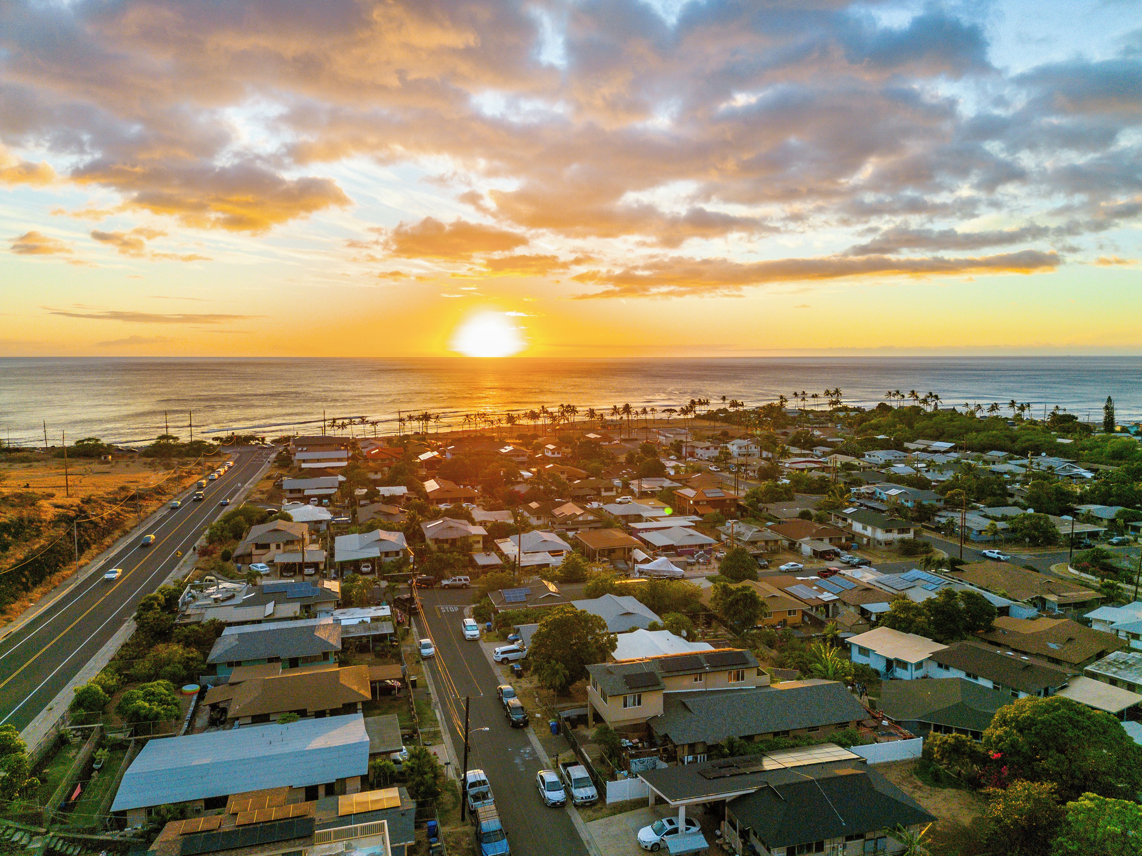 A coastal residential area with houses, a road, and a beach.
