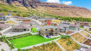 A residential area with houses, a central green space, and a mountain in the background. - Ocean View Exquisite Home at Cottages at Mauna Olu Near Beach W/outdoor Games (Waianae)