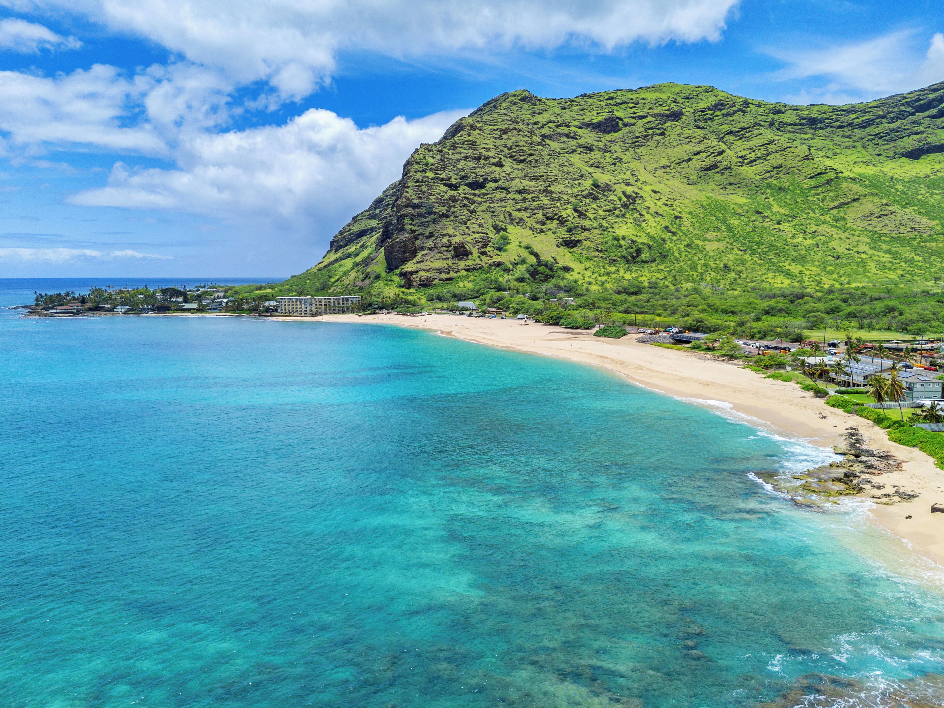 Une station balnéaire dotée d’une plage, d’une eau turquoise et limpide, et bordée par des montagnes.