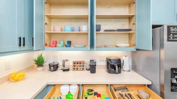 Una cocina moderna con armarios abiertos, una encimera con varios electrodomésticos y un organizador de cajones.