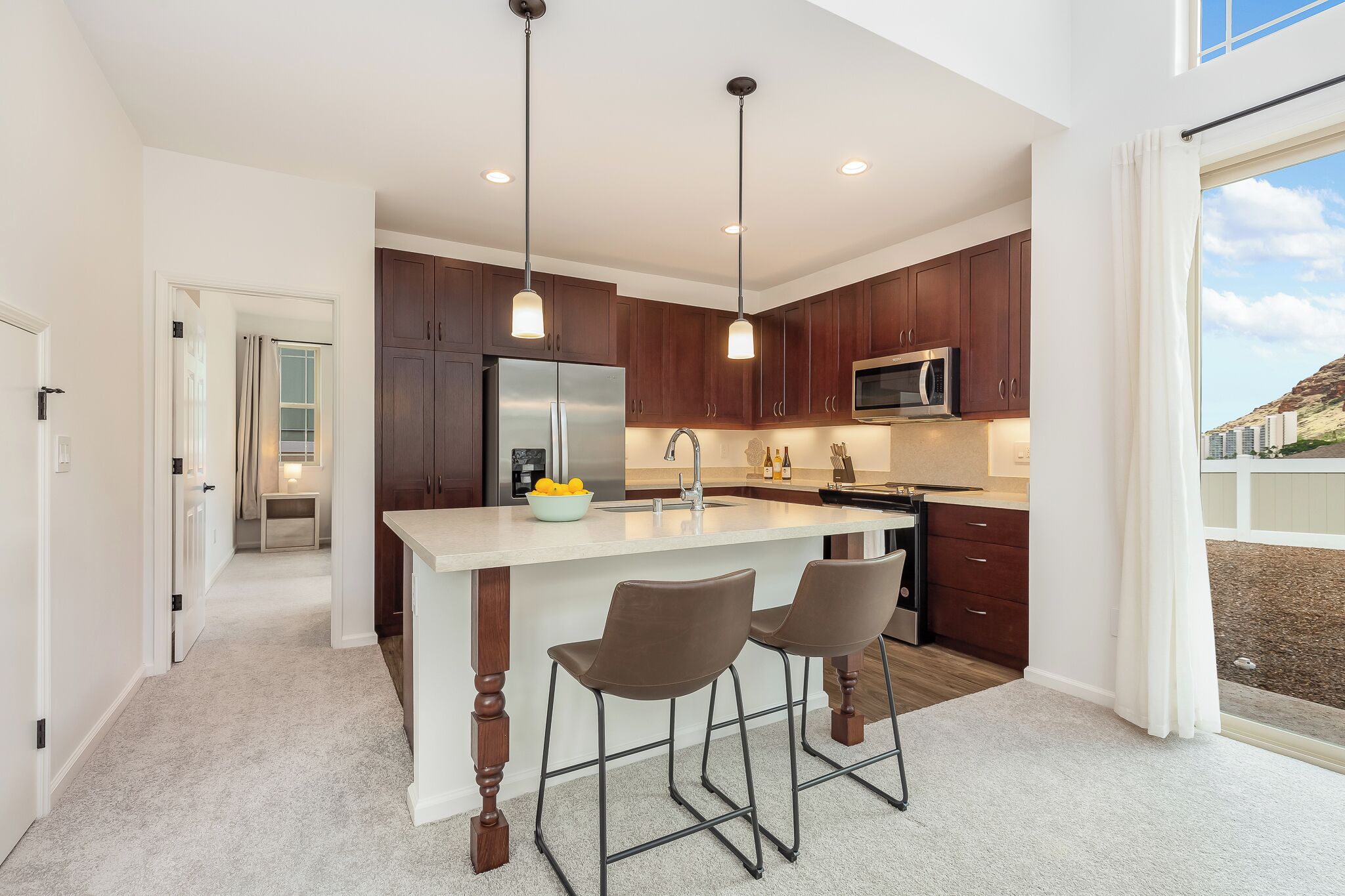 A modern kitchen with dark wood cabinets, stainless steel appliances, and a central island with bar stools.