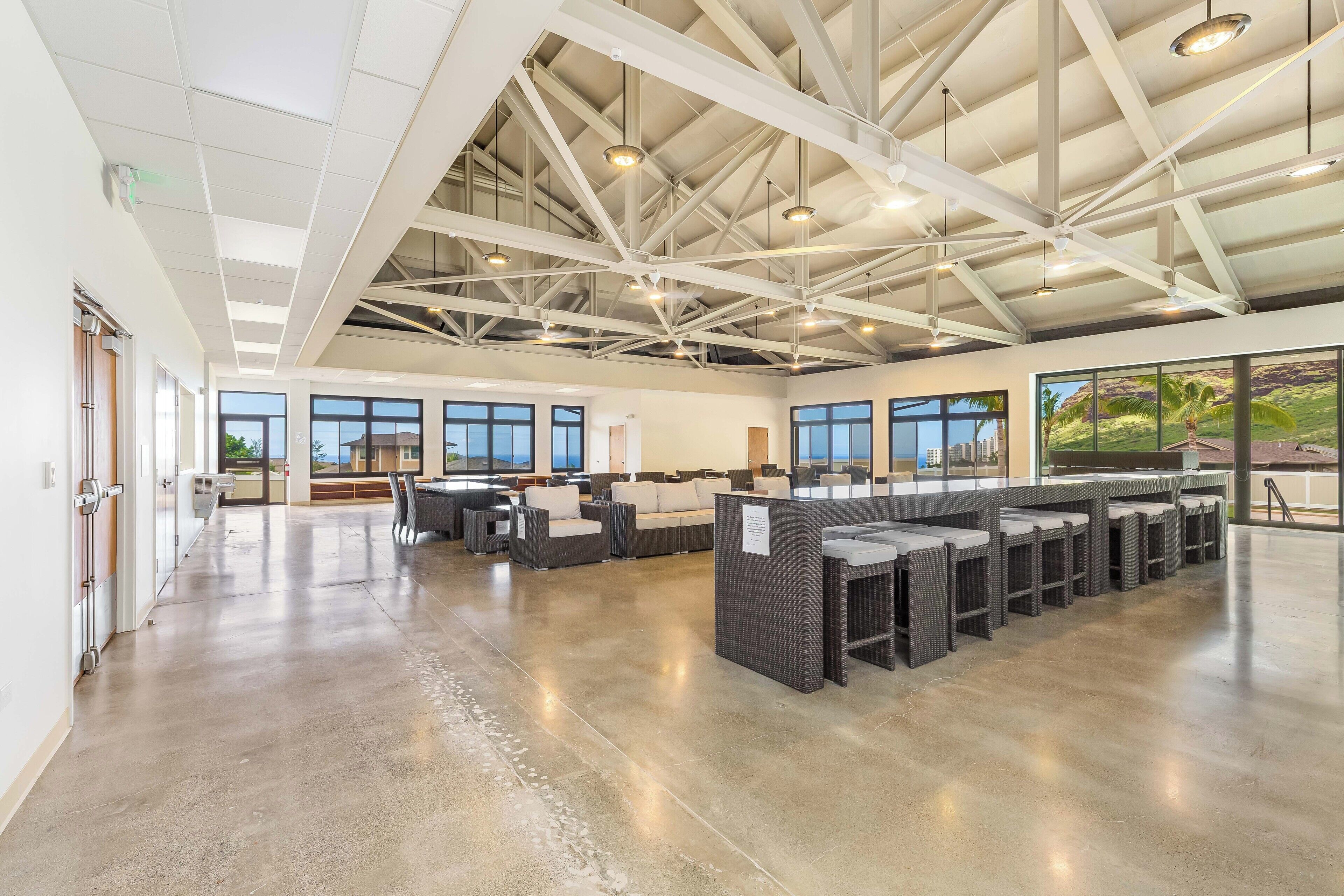 A spacious indoor area with a high ceiling, large windows, and a seating area with couches and tables.