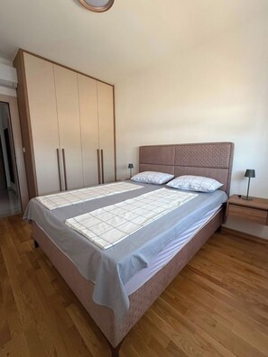 A bedroom with a bed, a wardrobe, a bedside table, and a lamp. - Peaceful 1-bedroom apartment with AC in charming Podgorica (Podgorica)