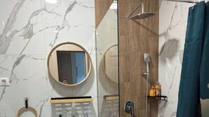Un bagno moderno con doccia vetrata, mobile bagno in legno, specchio rotondo e porta asciugamani.