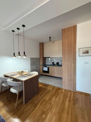 A modern kitchen with wooden cabinets, a built-in oven, and pendant lighting. - Peaceful 1-bedroom apartment with AC in charming Podgorica (Podgorica)