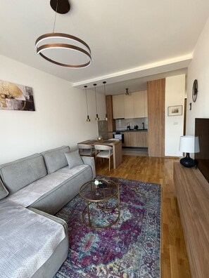 A modern living room with a grey sectional sofa, a coffee table, and a patterned rug. - Peaceful 1-bedroom apartment with AC in charming Podgorica (Podgorica)