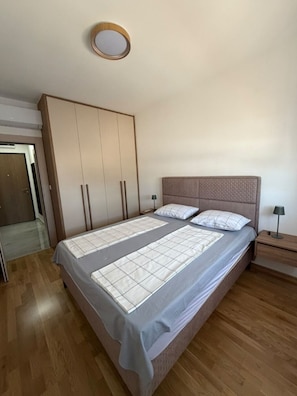 A bedroom with a bed, a wardrobe, a bedside table, and a nightstand. - Peaceful 1-bedroom apartment with AC in charming Podgorica (Podgorica)