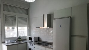 A compact kitchen with a washing machine, microwave, and a refrigerator. - Apartment 'Apartmento La Palmera' with Wi-Fi and Air Conditioning (Tarifa)
